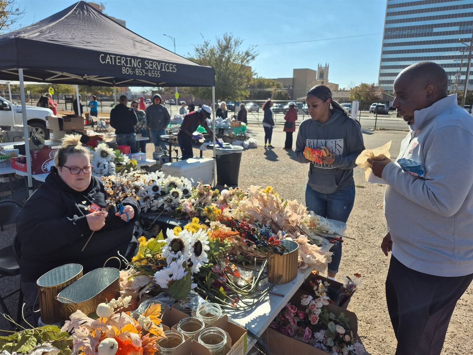 A volunteer seated at the table arranging stems as neighbors browse
