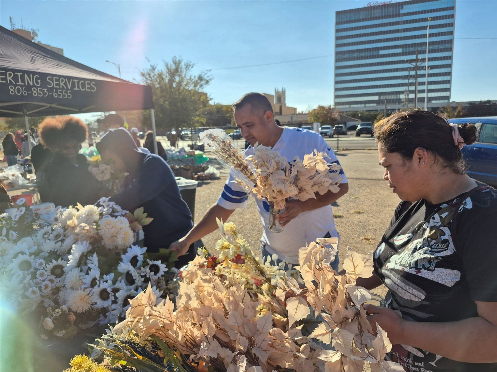 Neighbors picking stems at the flower table in the bright sun