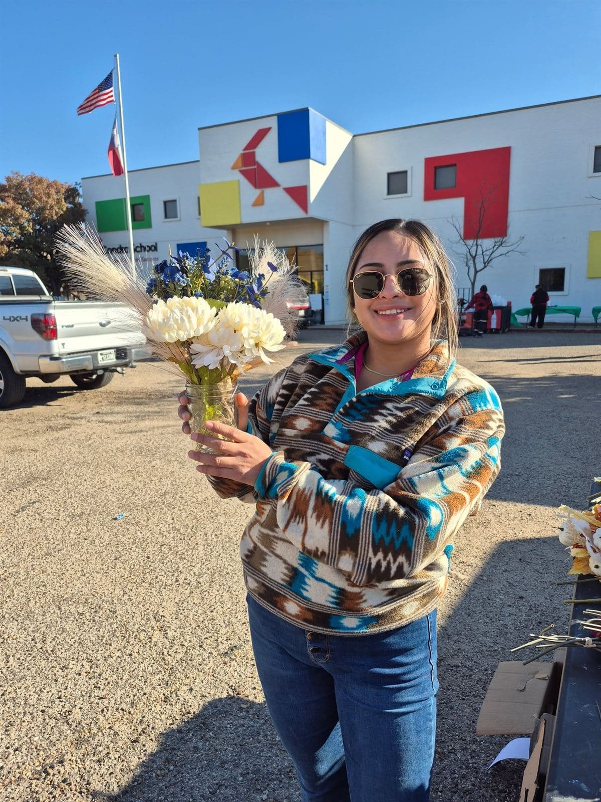 A neighbor holding a blue and white bouquet, the school behind her