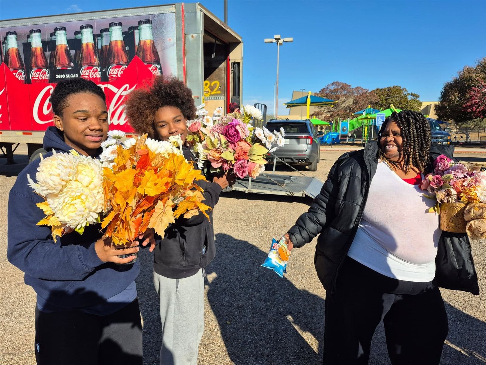 Two teens and a mom with bouquets in front of the Coca-Cola truck