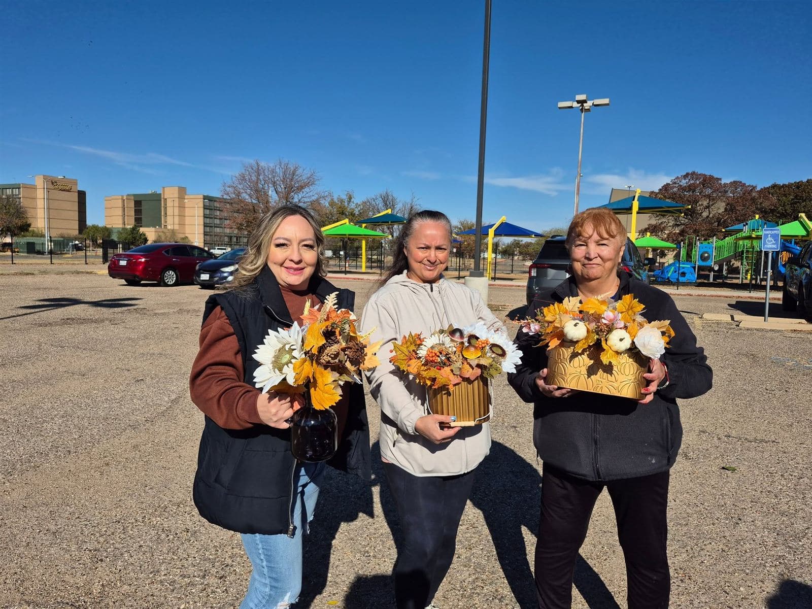 Three neighbors holding the fall arrangements they made