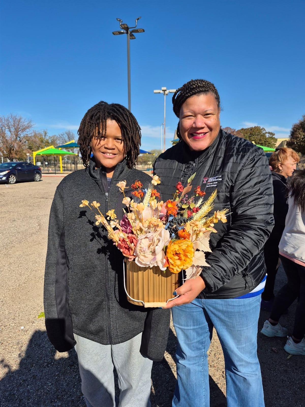 A woman and a young person holding an arrangement together