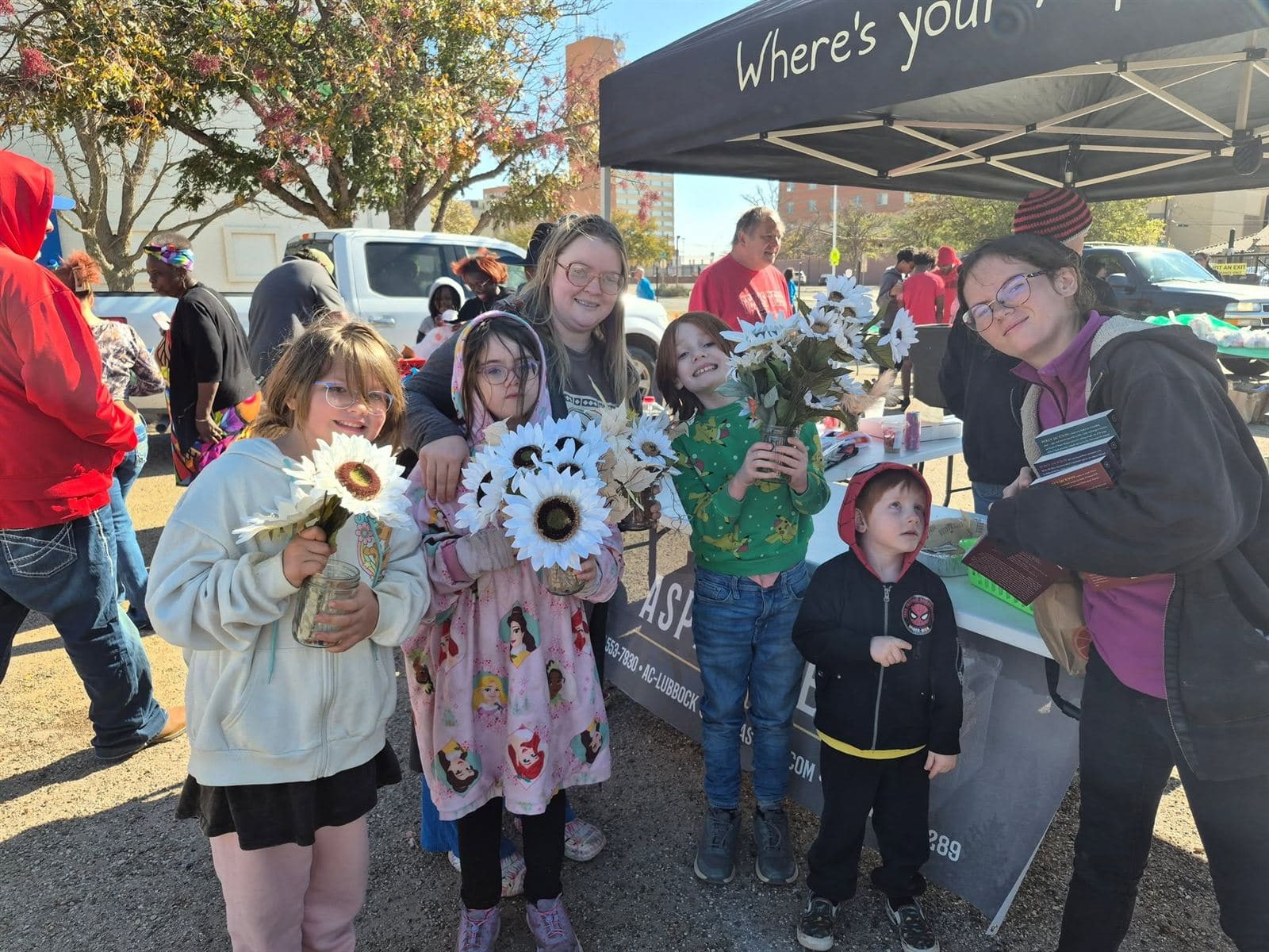 A group of young kids holding sunflowers with adults