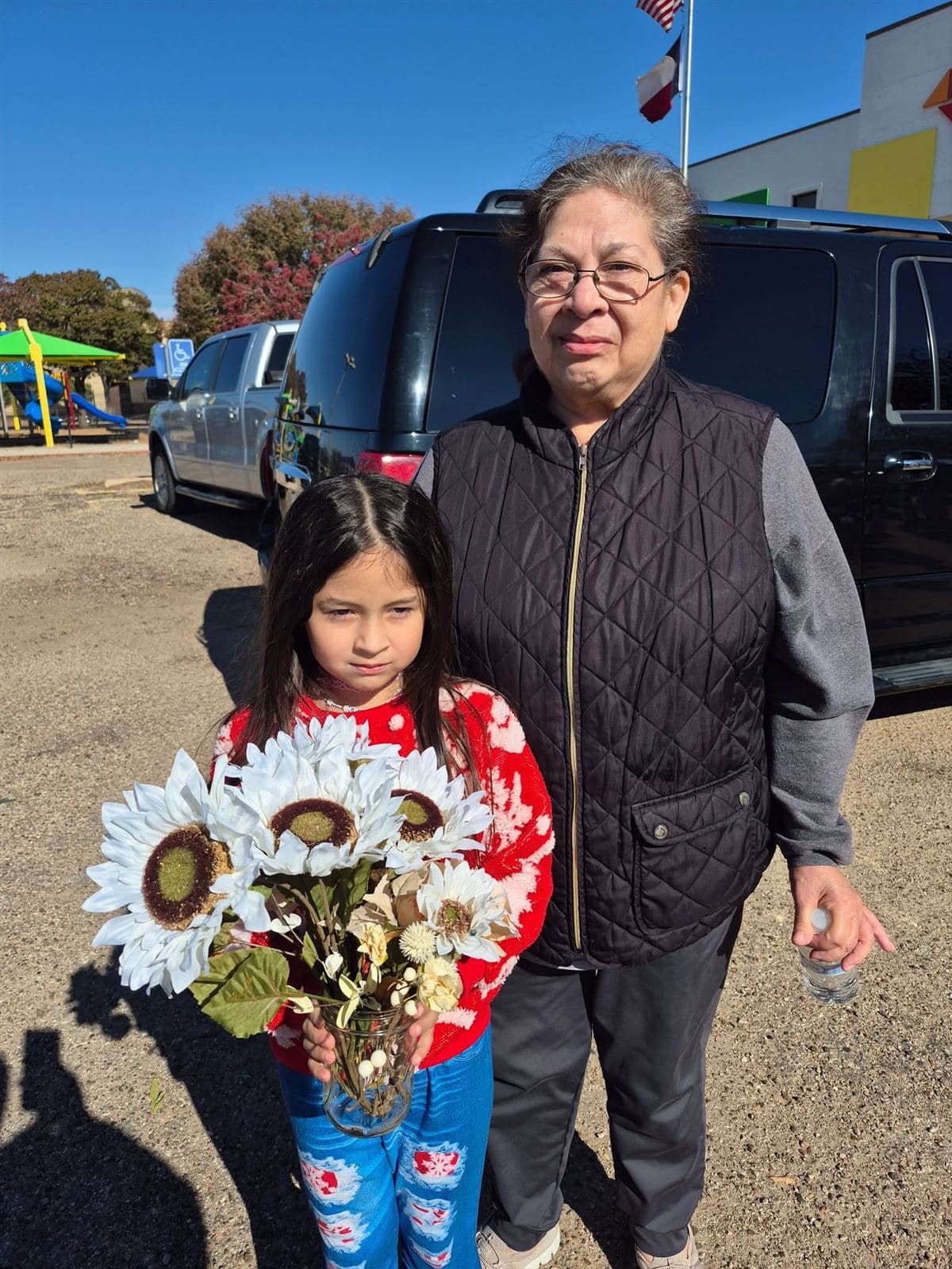 A grandmother and granddaughter, the girl holding sunflowers