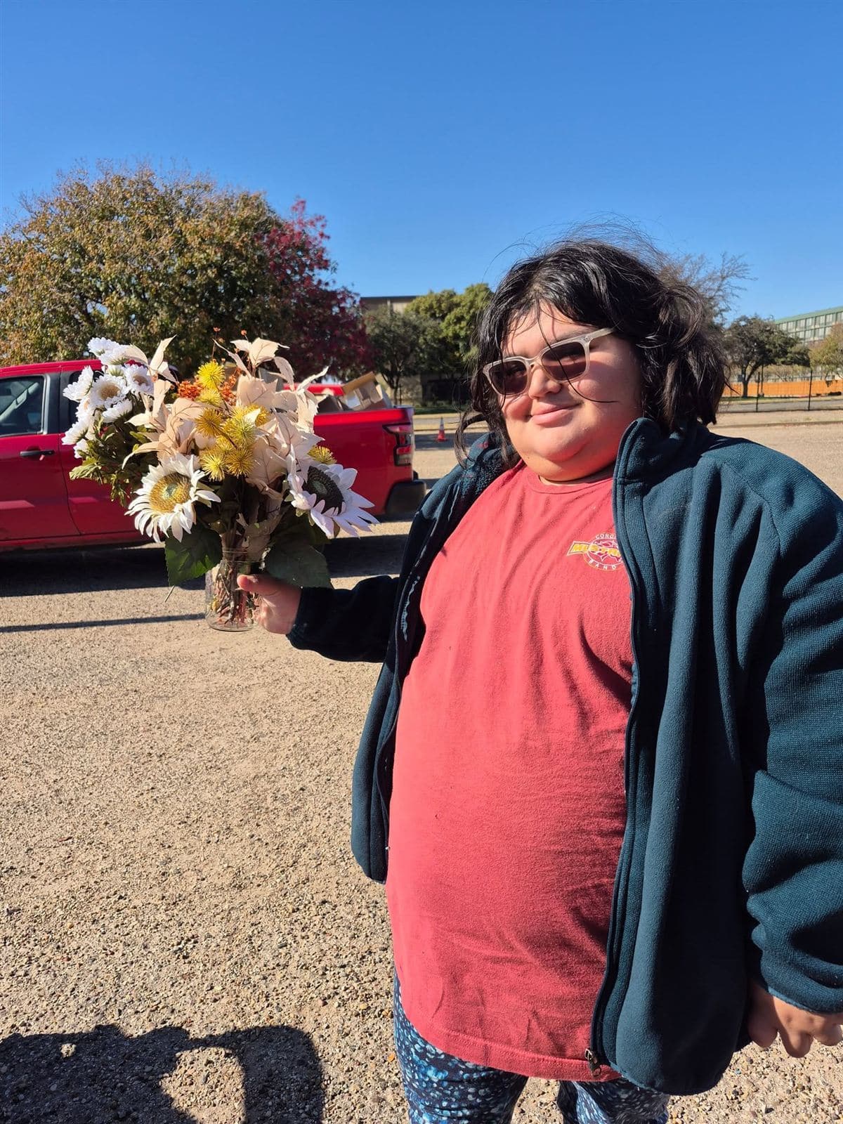 A young person in sunglasses holding a bouquet