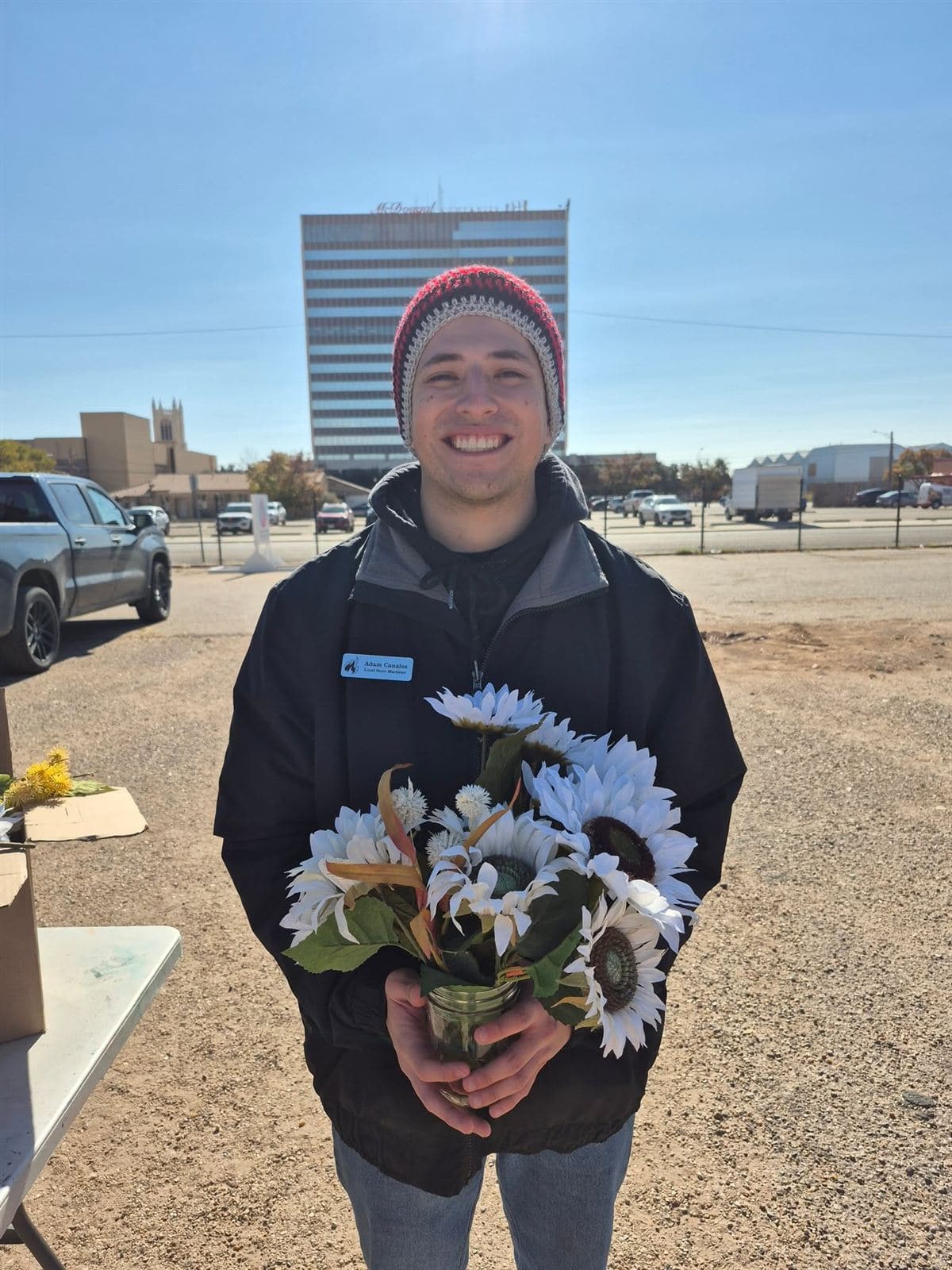 A young man in a beanie with a sunflower bouquet