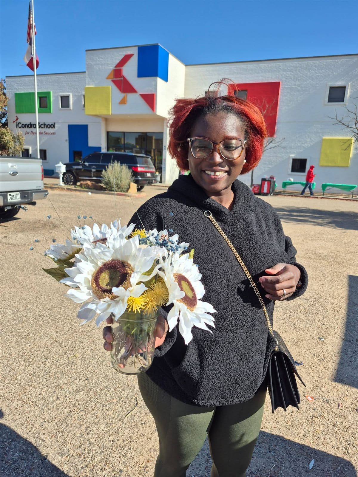 A neighbor holding a sunflower bouquet beside the school sign
