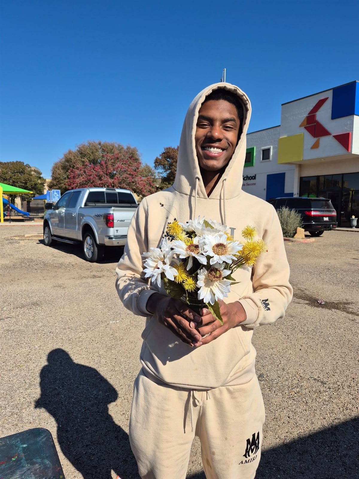 A young man in a hoodie with a daisy bouquet