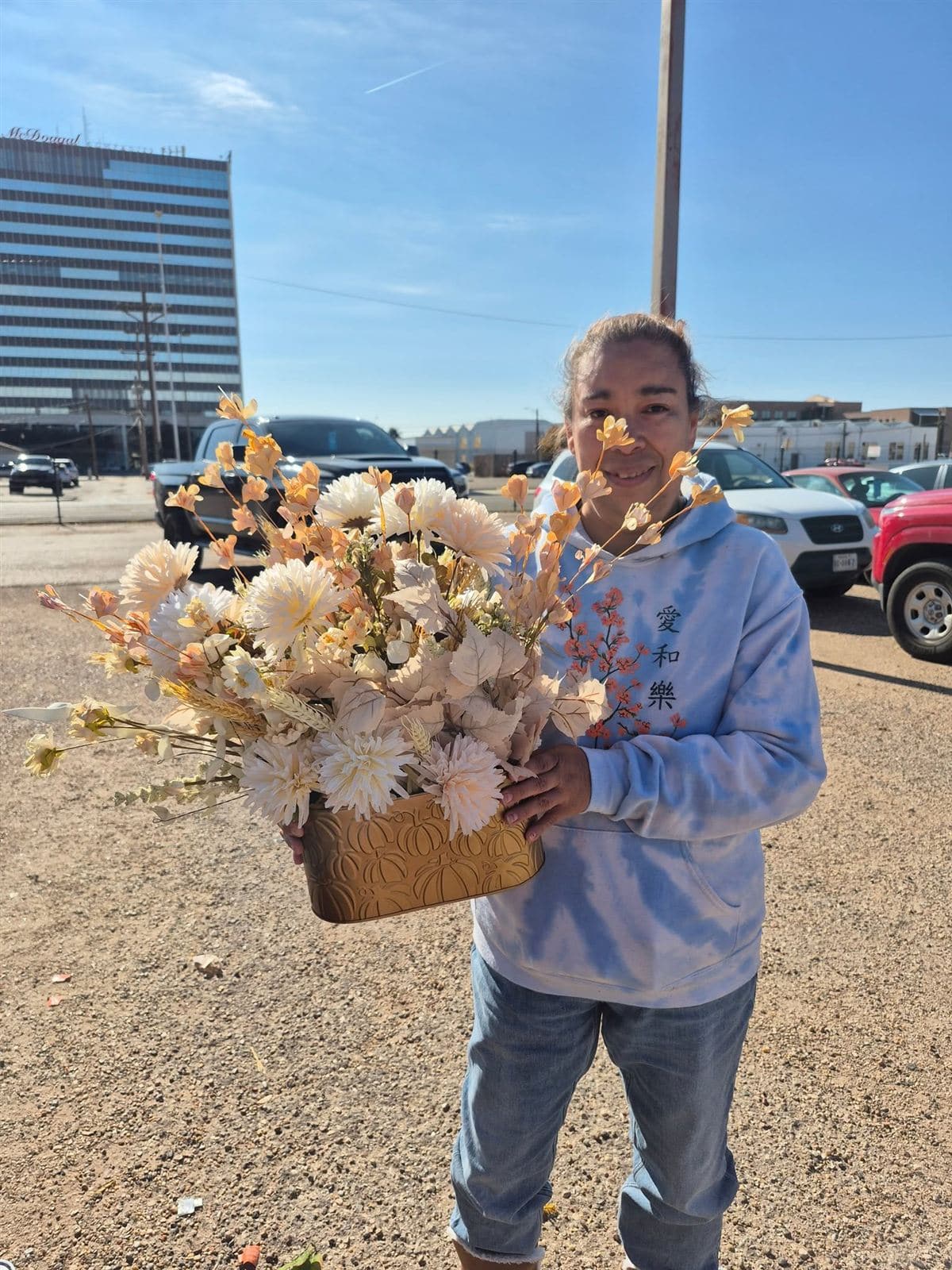 A neighbor holding a cream arrangement in a gold pot