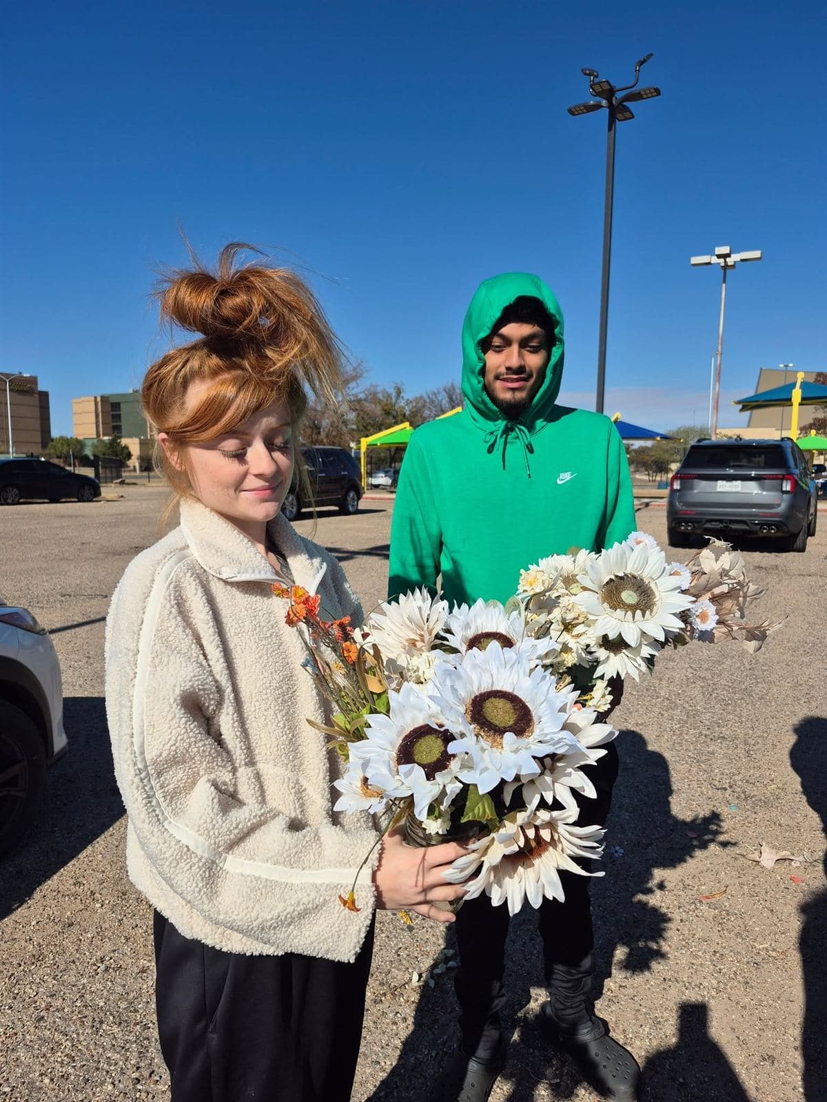 A young couple holding a sunflower bouquet