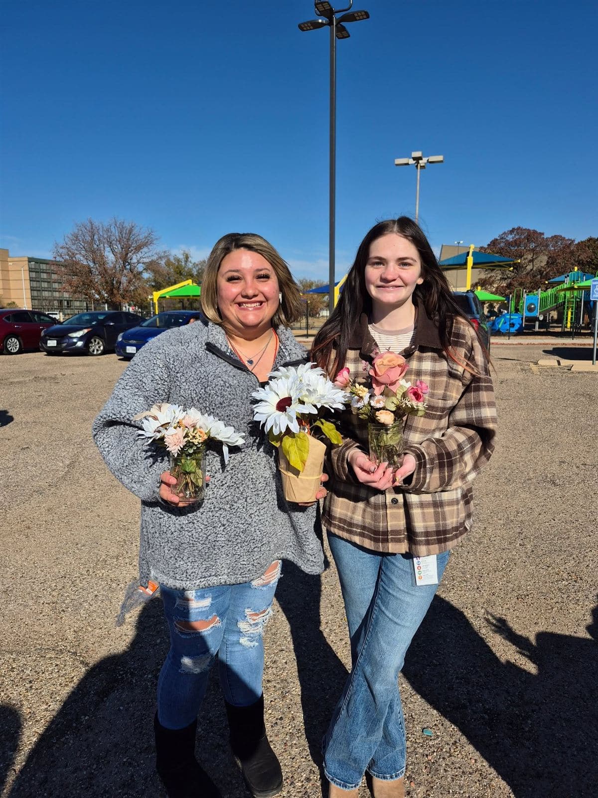 Two young women with small jar bouquets near the playground