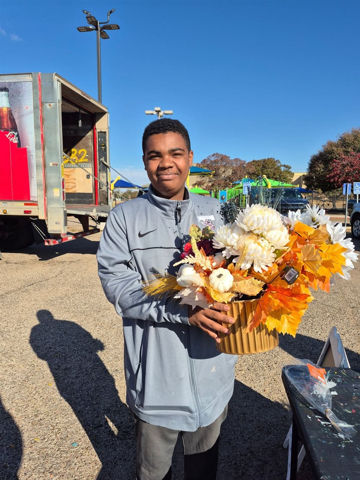 A teen proudly holding a large fall arrangement