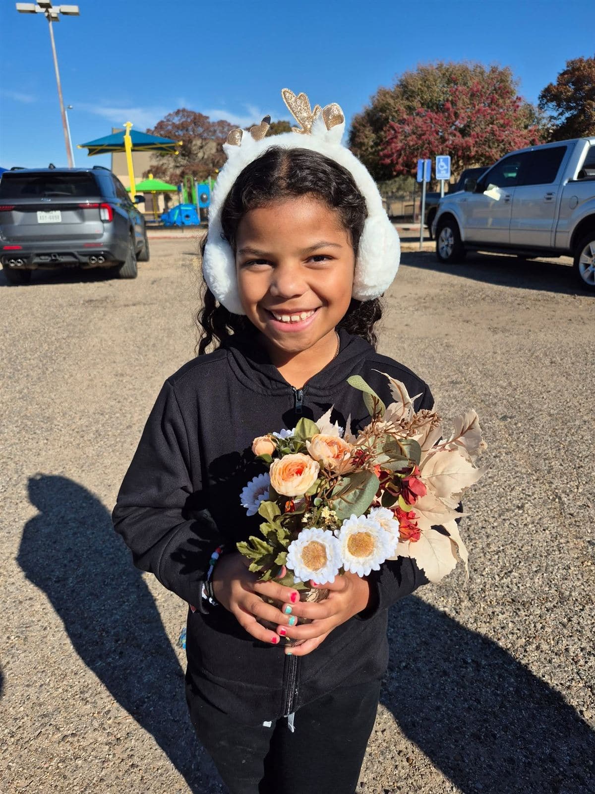 A girl in reindeer earmuffs with a big smile and her bouquet