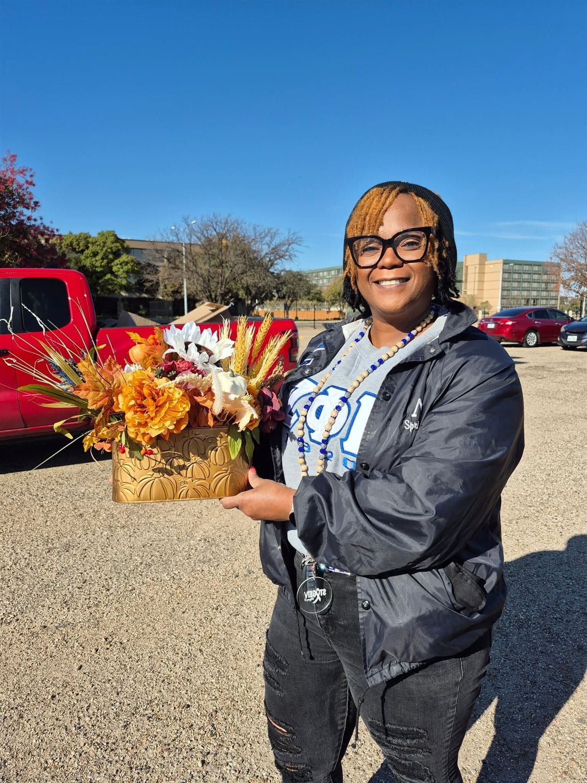 A volunteer holding a fall arrangement in a gold pot