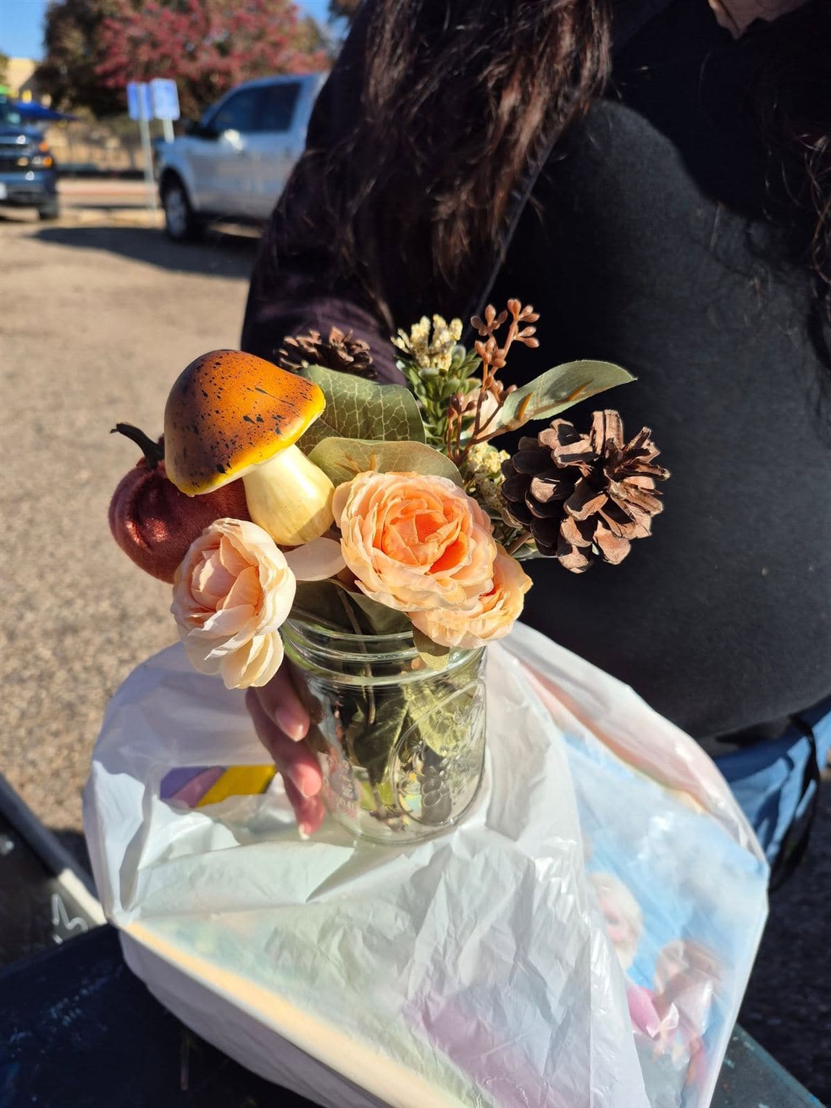 A mushroom and rose arrangement in a jar